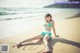 A woman in a bikini sitting on the beach.