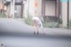 A woman in a white dress bending over on the street.