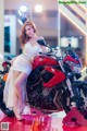 A woman in a white dress sitting on a red motorcycle.