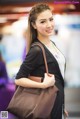 A woman holding a brown bag in an airport.