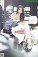 A woman in a white dress sitting on a motorcycle.