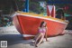 A woman in a bikini sitting on the beach next to a boat.