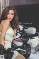 A woman in a white dress sitting on a motorcycle.