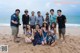 A group of people posing for a picture on the beach.