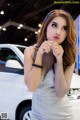 A woman in a silver dress standing next to a white car.