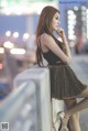 A woman in a black top and gold skirt leaning against a railing.