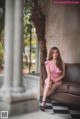 A woman in a pink dress sitting on a brown couch.