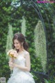 A woman in a wedding dress holding a bouquet of flowers.