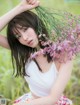 A woman sitting in a field holding a bunch of flowers.