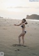 A woman in a blue bikini standing on a beach.