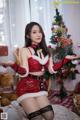 A woman in a red and black outfit posing in front of a Christmas tree.