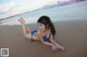 A woman in a blue bikini laying on the beach.