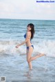 A woman in a blue bikini standing in the ocean.