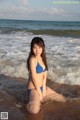 A woman in a blue bikini sitting in the water.