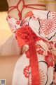 A woman in a red and white kimono sitting on a bed.