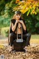 A woman sitting on top of a suitcase in a park.