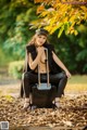 A woman sitting on top of a suitcase in a park.