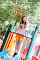 A young woman standing on a colorful playground slide.