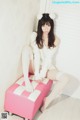 A woman sitting on top of a pink and white ottoman.