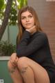 A woman in a black dress sitting on a bench.