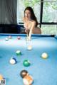 A woman is playing pool on a blue table.