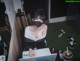 A woman wearing a face mask sitting at a desk with a laptop.