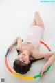 A young girl laying on the floor with a hula hoop.