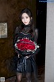 A woman in a black dress holding a bouquet of red roses.