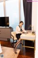 A woman sitting at a desk in front of a television.