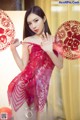 A woman in a red lingerie holding a red fan.