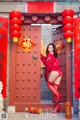 A woman in a red outfit standing in front of a red door.