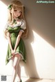 A girl in a green dress leaning against a wall.