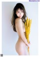 A naked woman holding a bunch of yellow flowers.