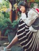 A woman in a black and white striped dress sitting on a bench.