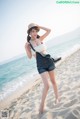 A woman standing on a sandy beach next to the ocean.