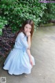 A woman in a blue and white striped dress sitting on the ground.