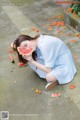 A woman in a blue dress eating a slice of watermelon.