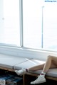 A woman sitting on a bench in front of a window.