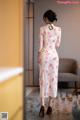 A woman in a white and red floral dress standing in a room.