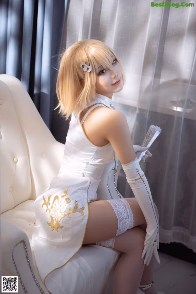 A woman in a white dress sitting on a white chair.