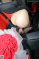 A woman sitting in the back seat of a car holding a bouquet of roses.