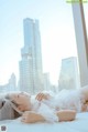 A woman laying on a bed in front of a window.