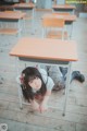 A young girl sitting at a desk in a classroom.