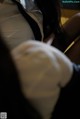 A woman in a white shirt and black tie sitting on a chair.