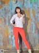 A woman in a white shirt and red pants posing for a picture.