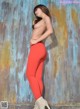 A woman in red leggings leaning against a rusty wall.