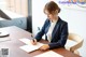 A woman sitting at a desk writing on a piece of paper.